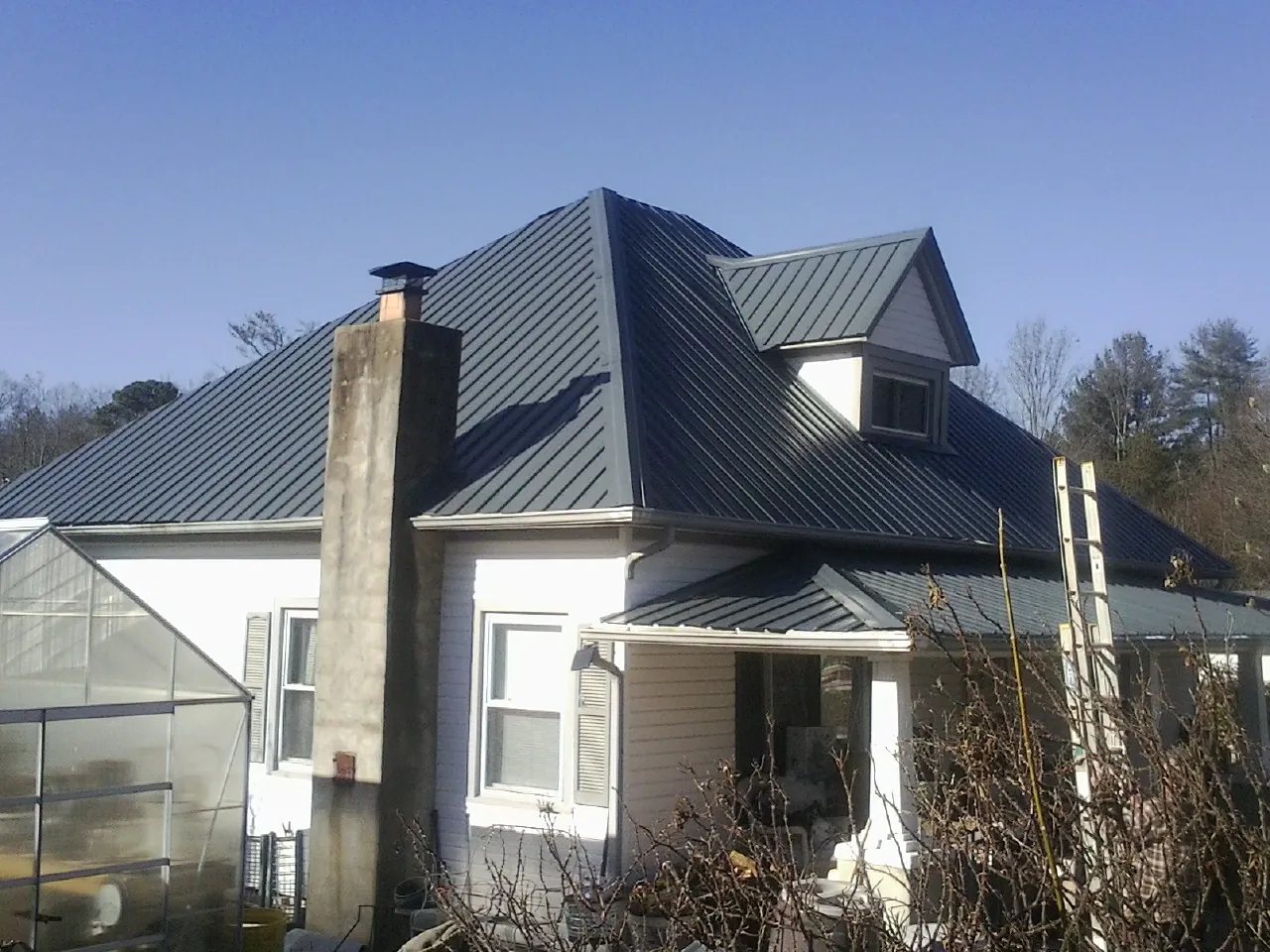 Dark blue standing seam metal roof on a white farmhouse with dormer — Slate & Tile Roof Repair by Roofing Brothers in West Hurley