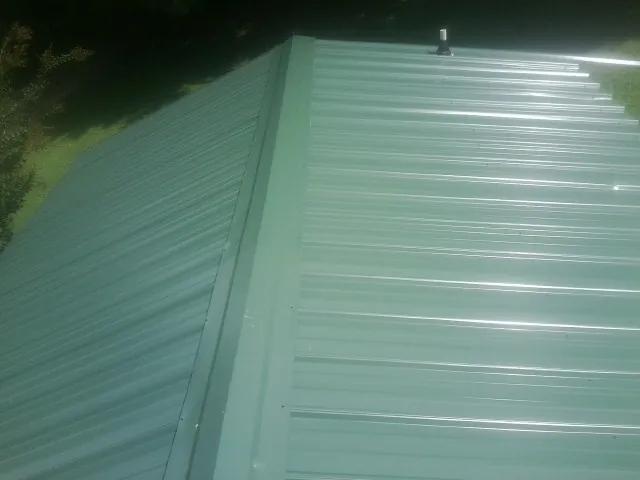 New green metal panels meeting at the ridge of a roof — Flat Roof Repair work by our crew in West Hurley