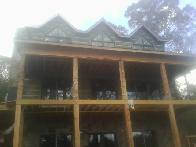 Dormers and porch framing on a large log home under construction — Roof Coating work by our crew in West Hurley