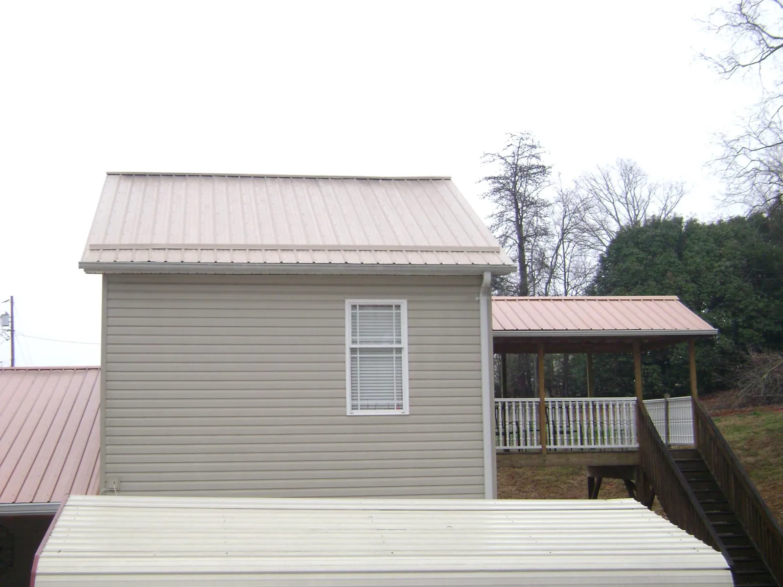 Tan metal roofs on a two story addition and attached porch, from a Roof Replacement job in West Hurley