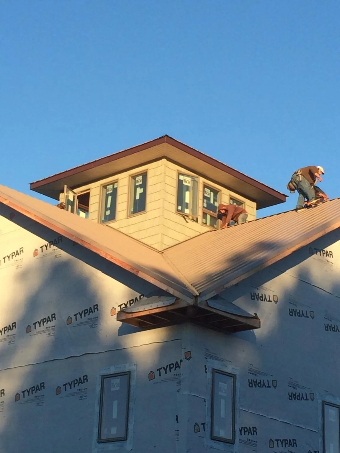 Roofers working around a rooftop cupola on a new metal roof at sunset — Roof Waterproofing in West Hurley by Roofing Brothers